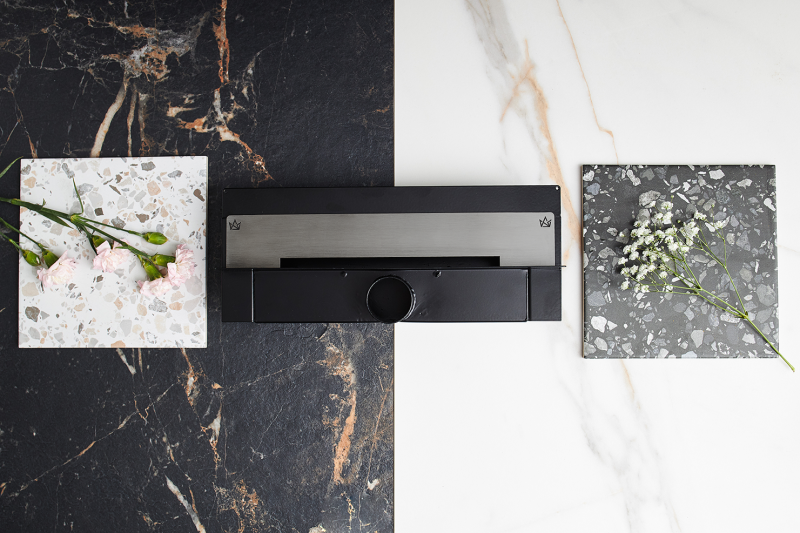 Super niski grafitowy odpływ ścienny w wykończeniu szczotkowanym na tle jasnej i ciemnej płytki