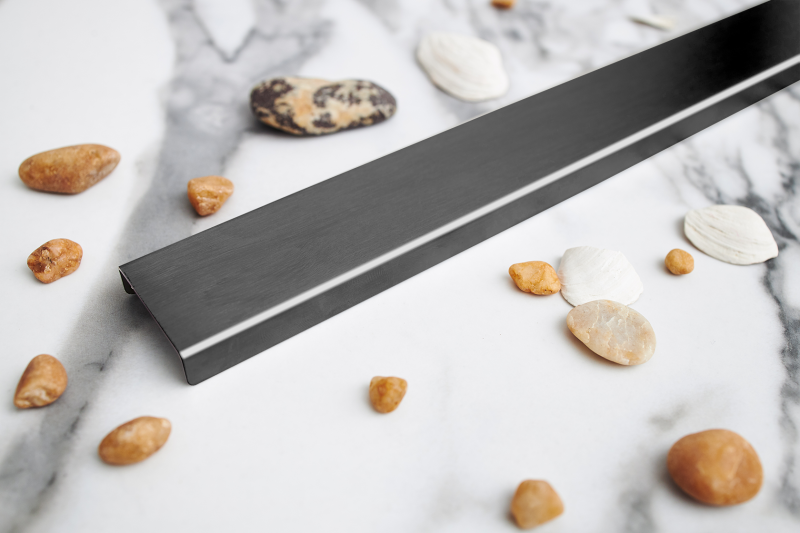 Odpływ liniowy przyścienny grafitowy szczotkowany na tle jasnej płytki.