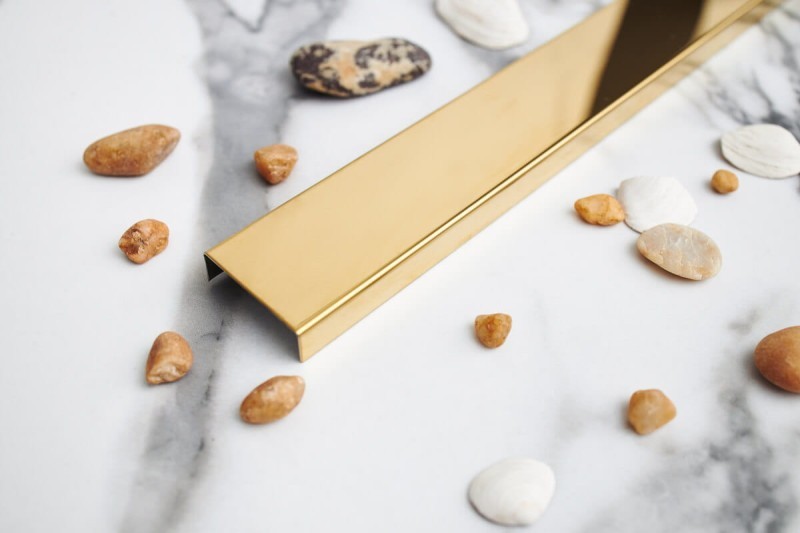 Odpływ przyścienny złoty na tle jasnej płytki