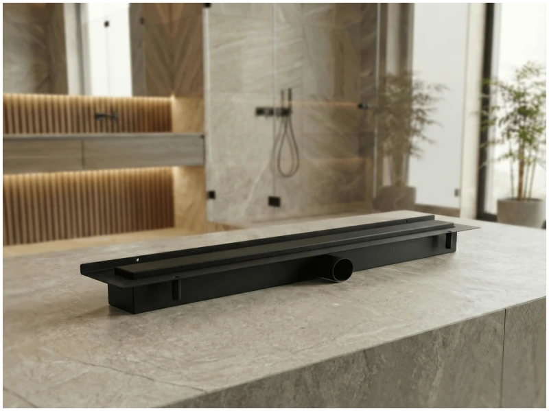 Czarny odpływ przyścienny na tle łazienki