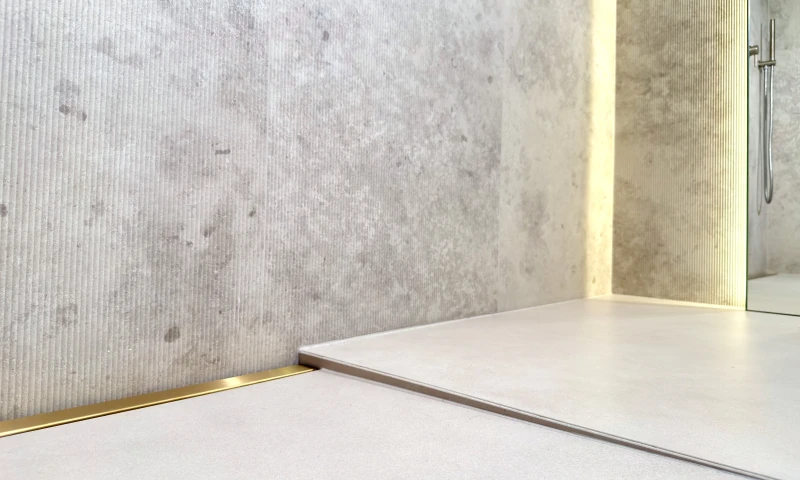 Złoty odpływ liniowy przyścienny na pełną szerokość prysznica