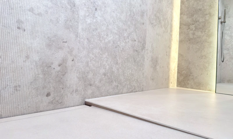 Łazienka z zabudowanym płytką odpływem przyściennym LINE PRO na pełną szerokość prysznica.