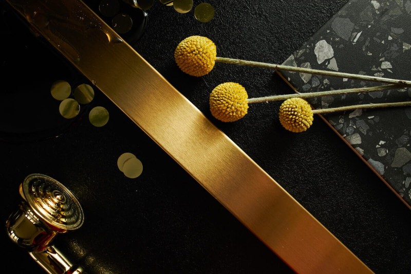 Zbliżenie na szczotkowaną strukturę złotego odpływu liniowego LINE PRO